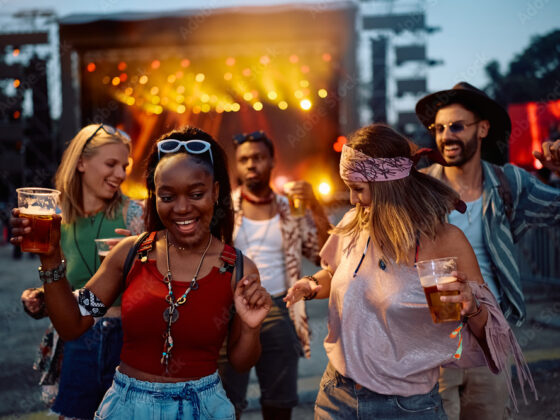 Cheerful friends dancing and having fun at summer music festival.